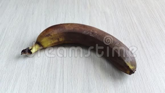 过熟的香蕉躺在木桌上雌性白手将成熟的热带水果从框架中取出特写白天丑陋视频的预览图