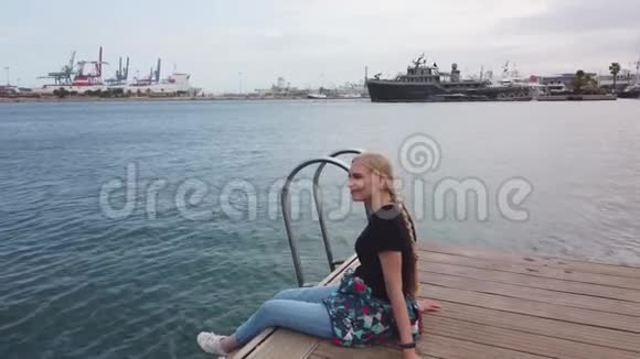 女人坐在一个木墩上看着大海感觉自由一片背景的海水碧水蓝天视频的预览图