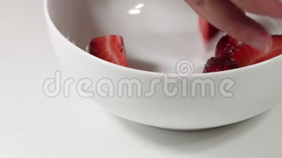 把新鲜成熟的草莓切成薄片放在白色背景的碗里视频的预览图