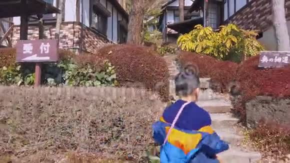 小男孩跑上楼梯进入日本山村度假的概念视频的预览图