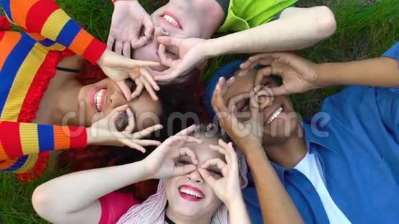 快乐的多种族青少年朋友做双筒望远镜手势在草地上休息快乐视频的预览图
