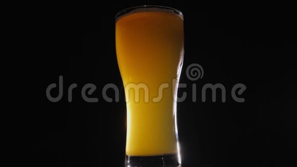 一杯轻啤酒的特写在黑色背景上慢慢旋转视频的预览图