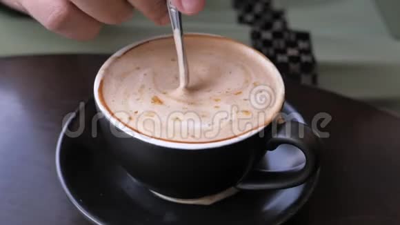 年轻女子用勺子搅拌一杯咖啡视频的预览图
