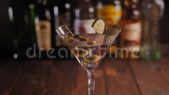 一个玛蒂尼玻璃的特写橄榄慢慢地酒吧与瓶子视频的预览图