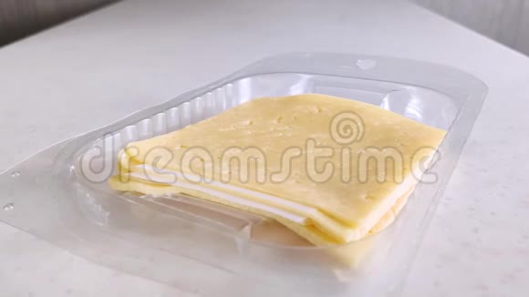 塑料包装中的方形黄色奶酪女白手拿一块有小孔的切片奶酪视频的预览图