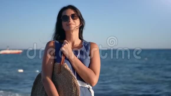 放松的旅行女性戴太阳镜在日落时在海景中拍照视频的预览图