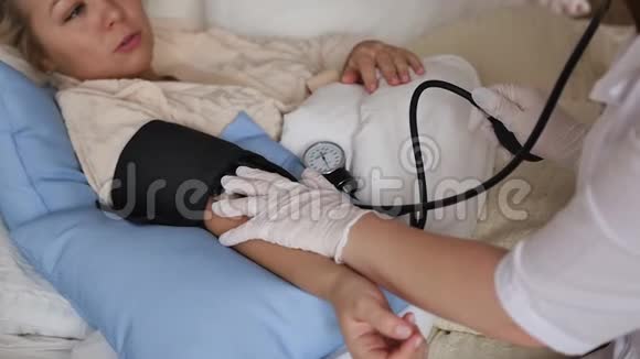 一位穿着白色外套的医生在床上休息时在家咨询一位妇女私人医生保健概念视频的预览图