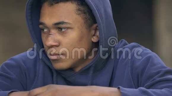 沮丧孤独的黑人有鼻子伤疤的少年独自坐着思考生活视频的预览图