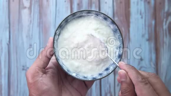 希腊酸奶在一个木制的碗在一个乡村木制的桌子上视频的预览图
