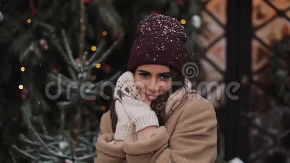 可爱的小姑娘穿着冬装站在雪花飘落的地方微笑着双手靠近视频的预览图