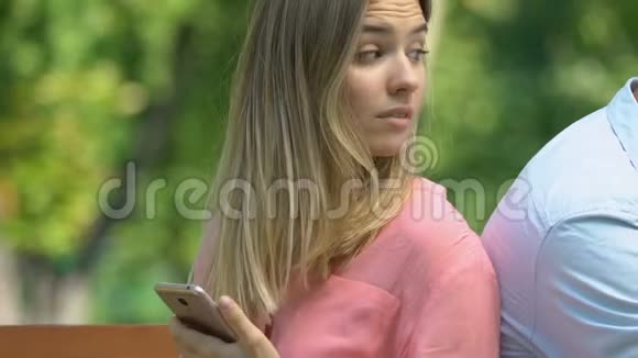 嫉妒的女人看着男朋友在手机上聊天不信任视频的预览图