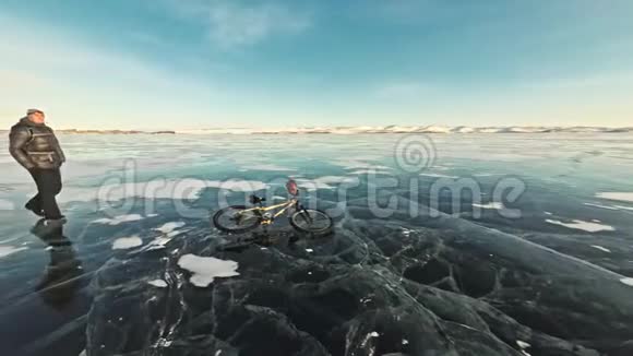 人在冰上骑着自行车走骑自行车的人穿着灰色羽绒服背包和头盔冰的冰视频的预览图