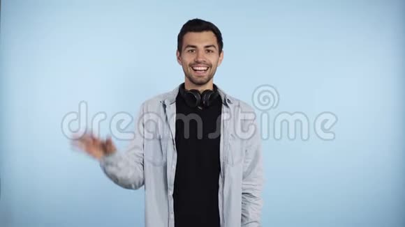 一个身穿蓝色衬衫的英俊的白种人站着看着牙齿般的微笑惊讶和挥手视频的预览图