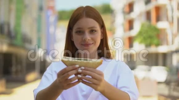 年轻快乐的女性在镜头上展示新鲜的三明治微笑的健康的零食视频的预览图