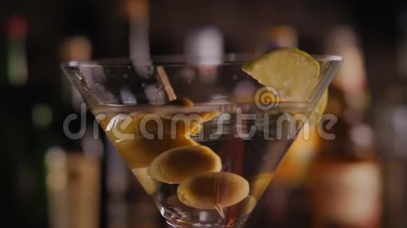 用橄榄慢慢旋转的马提尼酒杯用瓶子在酒吧里特写视频的预览图