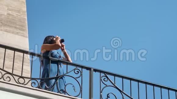 快乐旅行女人在蓝天背景的露台上用相机拍照视频的预览图