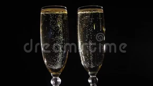 两杯香槟气泡在黑色背景上慢慢旋转视频的预览图