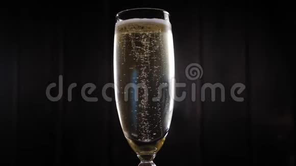 一杯香槟的特写镜头在黑色背景下旋转视频的预览图