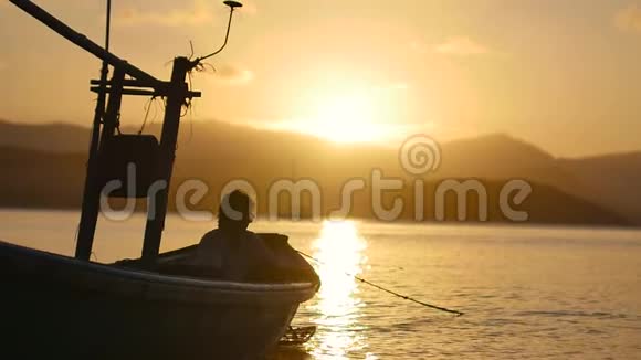 黎明时在平静的海面上的渔夫的剪影美丽的日落海上有一艘渔船的轮廓视频的预览图