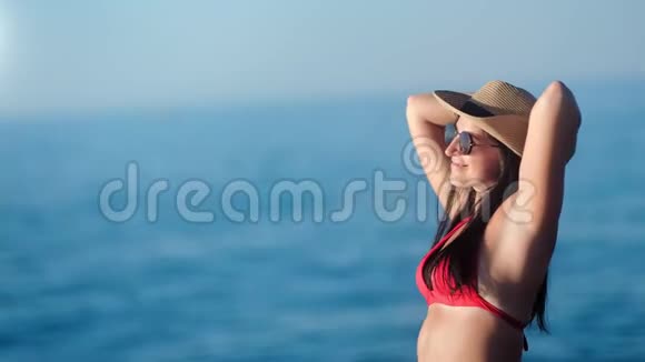 穿着比基尼戴着帽子在日落时玩得开心的晒黑皮肤的女人视频的预览图