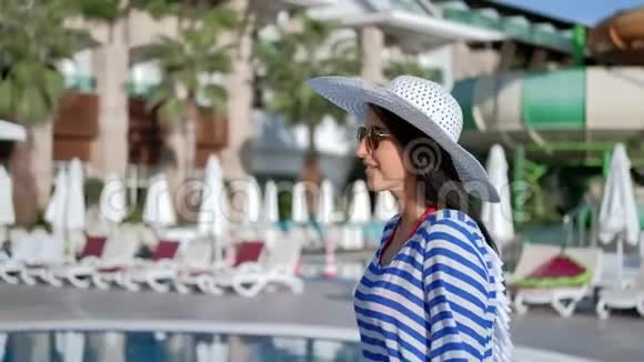 微笑轻松的旅行女孩太阳镜和帽子走在豪华度假区享受假期视频的预览图