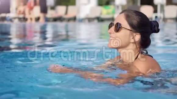 放松的度假者皮肤晒黑微笑着漂浮在海滩度假胜地的泳池边视频的预览图