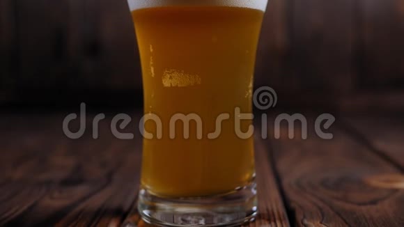 一名酒保在木制背景下将啤酒倒入玻璃杯中的特写镜头视频的预览图