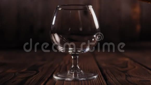 白兰地酒是从一个瓶子倒入一个玻璃在一个木制的背景慢动作视频的预览图