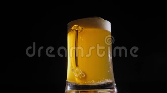 清蒸玻璃杯中的淡啤酒在黑色背景下缓慢旋转视频的预览图