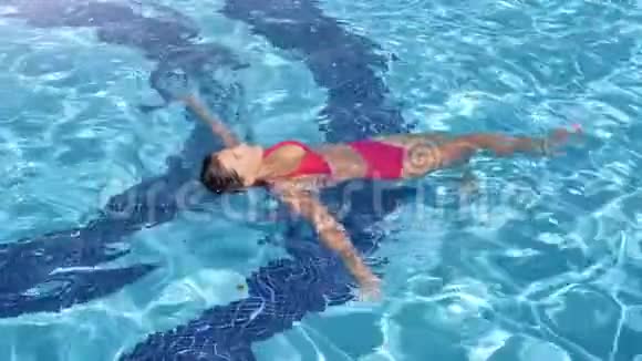 穿比基尼的女人在游泳池里游泳周围是清澈明亮的水慢动作视频的预览图