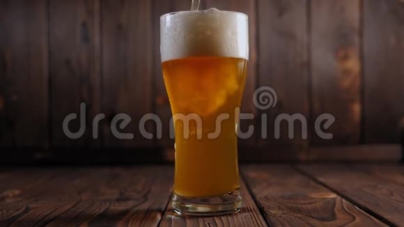特写的啤酒倒入一个杯子上的木质背景大量的泡沫视频的预览图