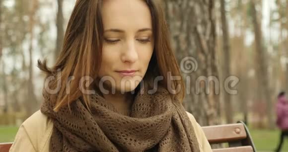 年轻可爱的女人在公园里读一本书的肖像她的头发随风飘动视频的预览图