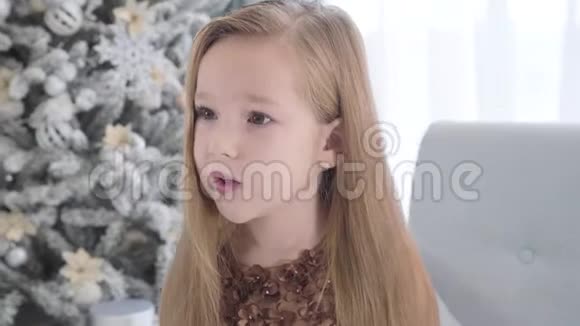 镜头围绕着一个长着长发的可爱白人女孩的脸移动坐在新街圣诞树旁的漂亮孩子视频的预览图