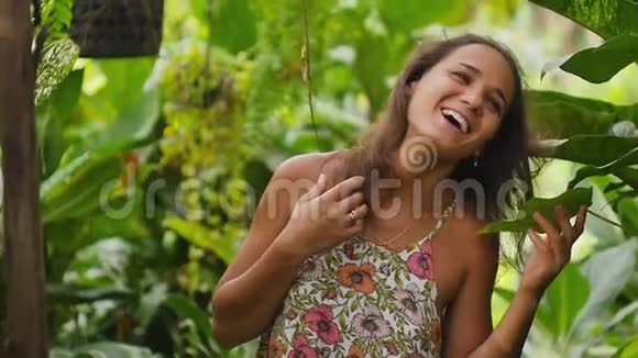 慢动作一个女孩走着穿着一件漂亮的夏装玩着探索热带花园视频的预览图
