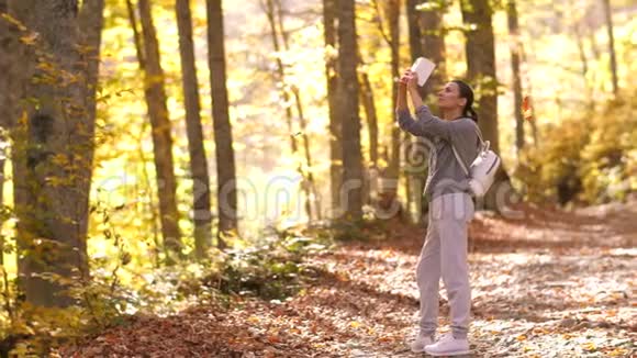 女人捕捉美丽的秋天公园视频的预览图