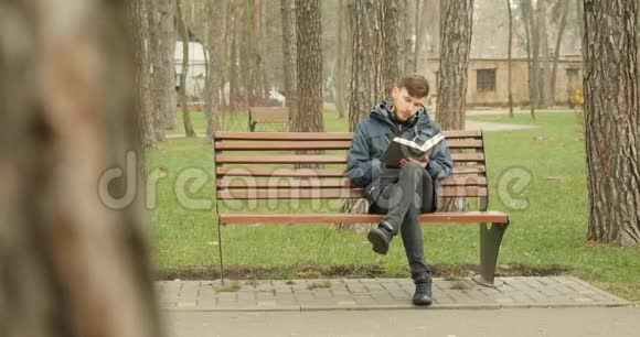 小胡子男在秋天的公园里读完一本书从长凳上站起来离开了其他地方阅读概念视频的预览图