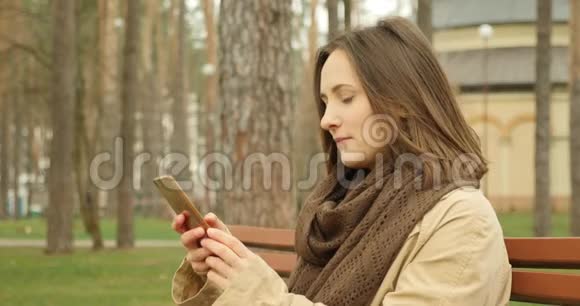 年轻的女性拿着手机在社交网络上滑动和滚动微笑和欢笑享受着她的社交生活实习生视频的预览图