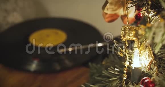 记录旋转在一个转盘的背景下一个小装饰圣诞树与发光灯在平安夜视频的预览图