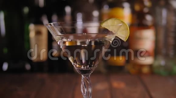酒保把橄榄放在瓶子背景的酒吧里的马丁尼玻璃里视频的预览图