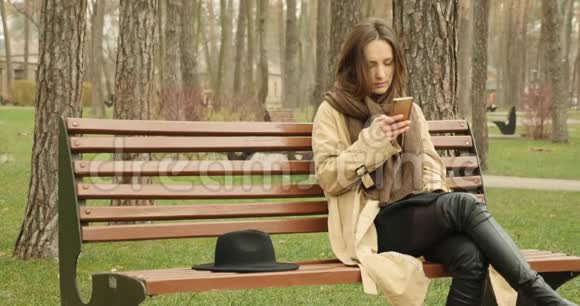 有手机的女人坐在公园的长椅上在社交网站上滚动享受她的闲暇时光社会网络视频的预览图