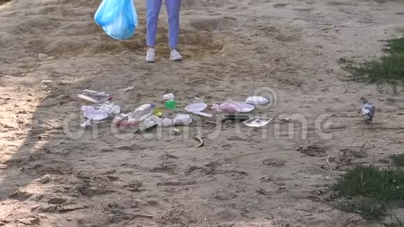 女志愿者帮助清洁垃圾海滩沙子上有很多垃圾视频的预览图