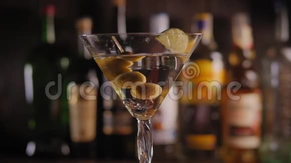 一个玛蒂尼玻璃的特写橄榄慢慢地酒吧与瓶子视频的预览图