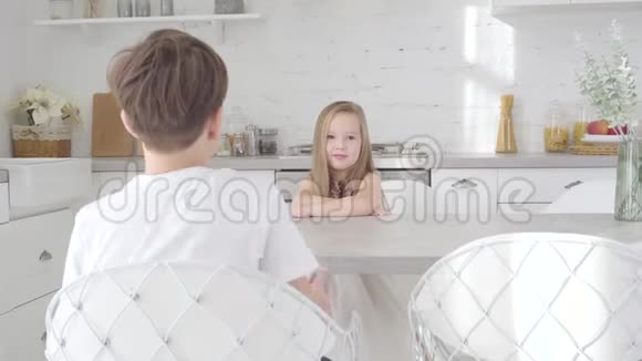 一幅可爱的白种人女孩坐在桌子旁黑发男孩送她的礼物盒小女孩收到礼物视频的预览图