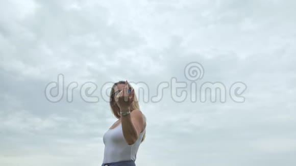 镜头跟随时髦的年轻女人穿着白色的t恤短牛仔裤飘扬的长发一个女孩在便携式电脑前跳舞视频的预览图