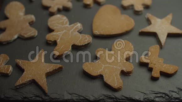 姜人形状的饼干心和星星放在黑色的盘子上被白色的粉末糖洒下视频的预览图