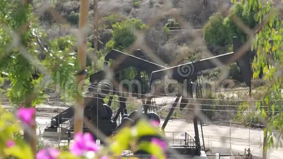 工业城市景观洛杉矶的拉布雷亚英格尔伍德井泵千斤顶在栅栏后面工作钻机视频的预览图