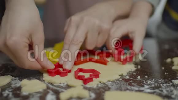 把成人和儿童的手合在一起煮不同形状的饼干面团孩子们帮妈妈在桌子上做糖果视频的预览图