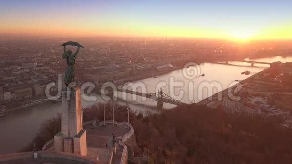 匈牙利布达佩斯日出时无人驾驶飞机飞越自由女神像上空飞往自由桥的4K空中镜头视频的预览图