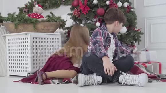 白人儿童在圣诞树下带礼物的肖像转向相机微笑男孩和女孩花钱视频的预览图