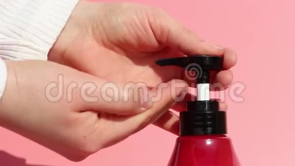 女用手挤肥皂配液器粉红色背景视频的预览图